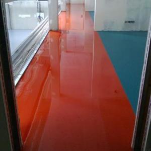 Glänzender, oranger Bodenbelag in einem modernen Innenraum mit weißen Wänden und großen Fenstern