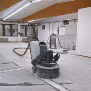 Bodenreinigungsmaschine in einem großen, leeren Raum mit weißen Wänden und sichtbaren Deckenbalken