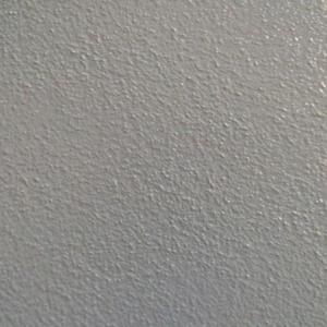 Nahaufnahme eines grauen, strukturierten Bodenbelags mit unregelmäßiger Oberfläche